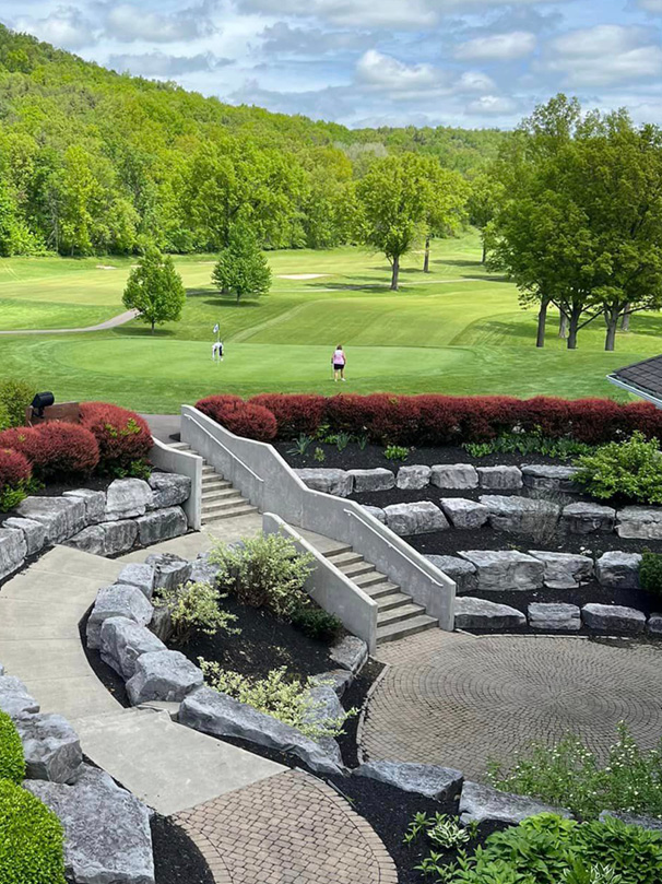A beautifully manicured golf course with a green field and a path leading to the course.

Description generated by AI