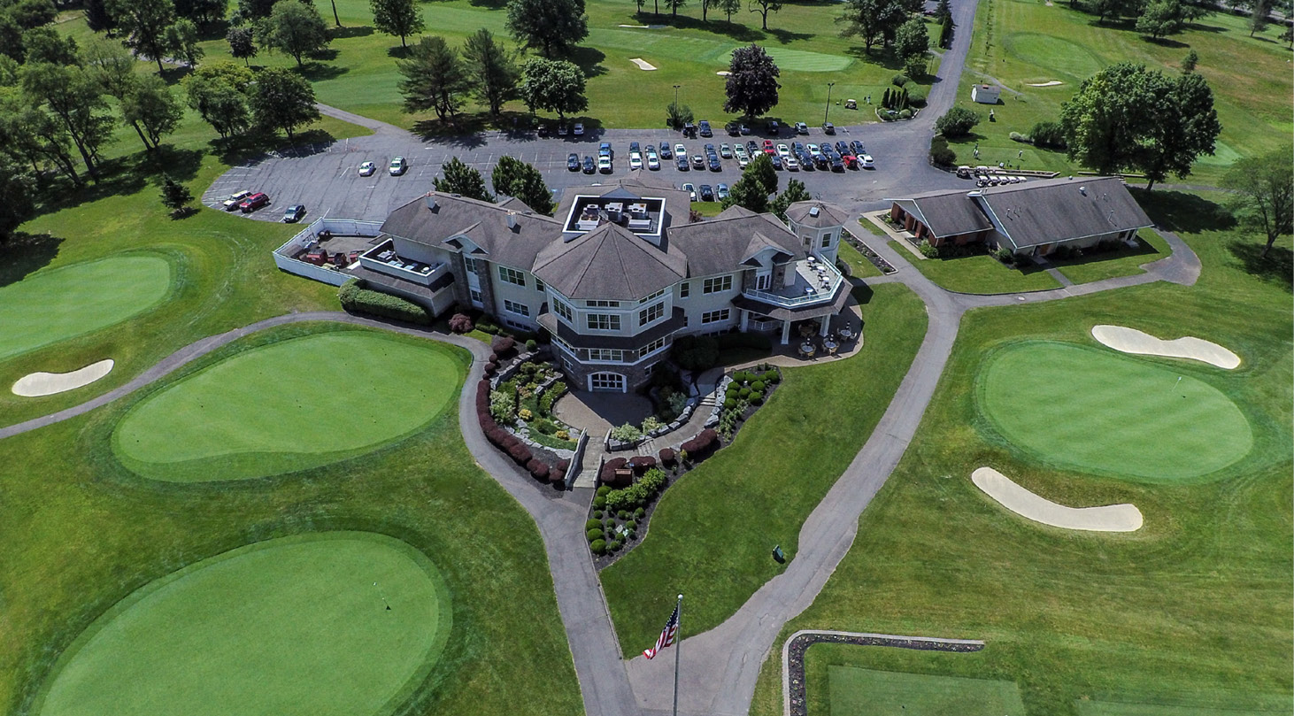 A green golf course with a white building in the background.

Description generated by AI